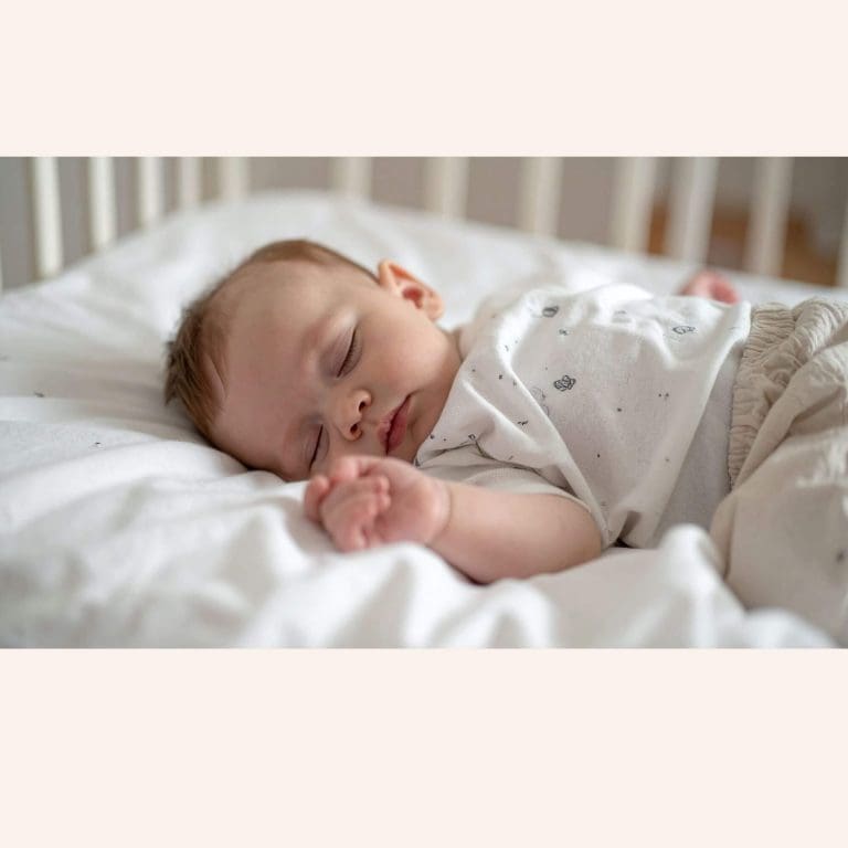 ébé dormant sur le dos dans un lit à barreaux sécurisé avec gigoteuse