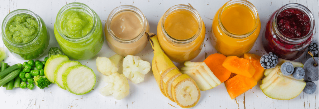 Pots en verre de conservation remplis de purées colorées pour bébé, avec fruits et légumes frais.