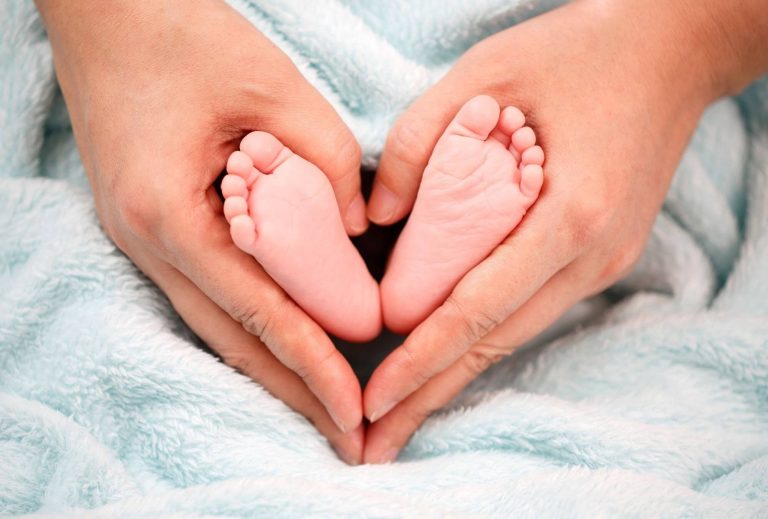 idée cadeau naissance - mains en cœur autour des pieds de bébé nouveau-né