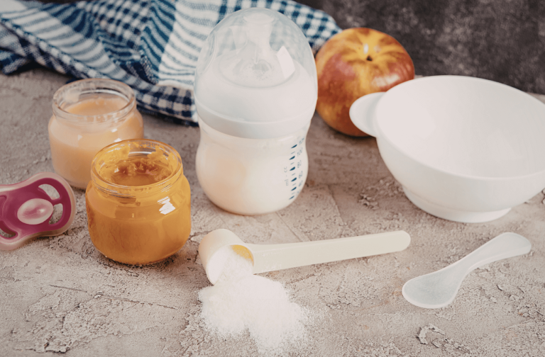 Biberon de lait infantile et petits pots de purée bébé posés sur une surface, symbolisant la place du lait pendant la diversification