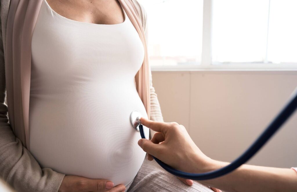 Sage-femme ausculte le ventre d'une femme enceinte lors d'une consultation prénatale