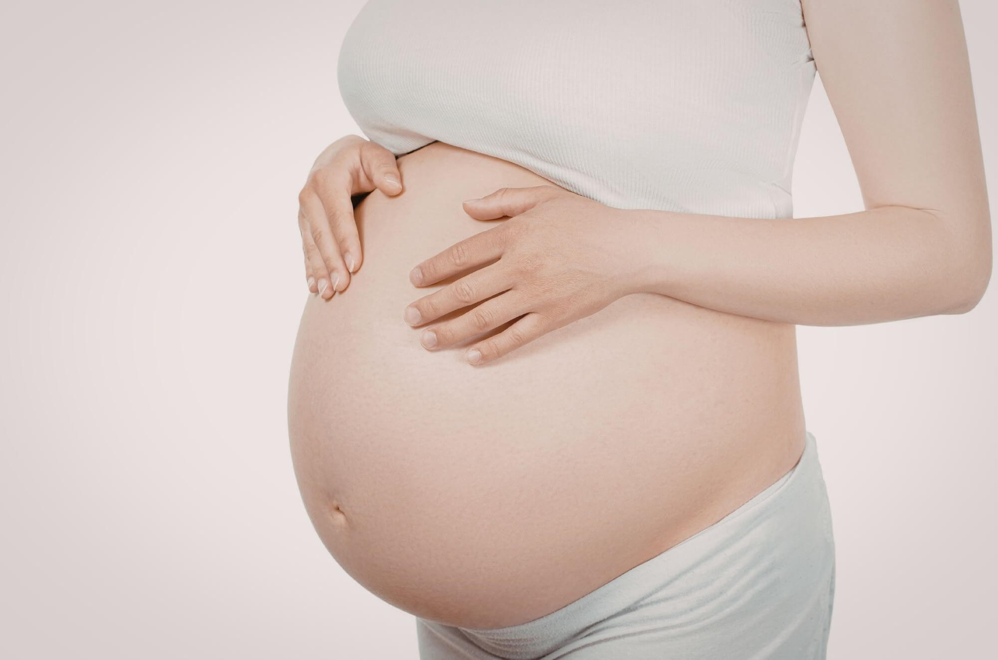 Femme enceinte tenant son ventre à deux mains pendant la grossesse