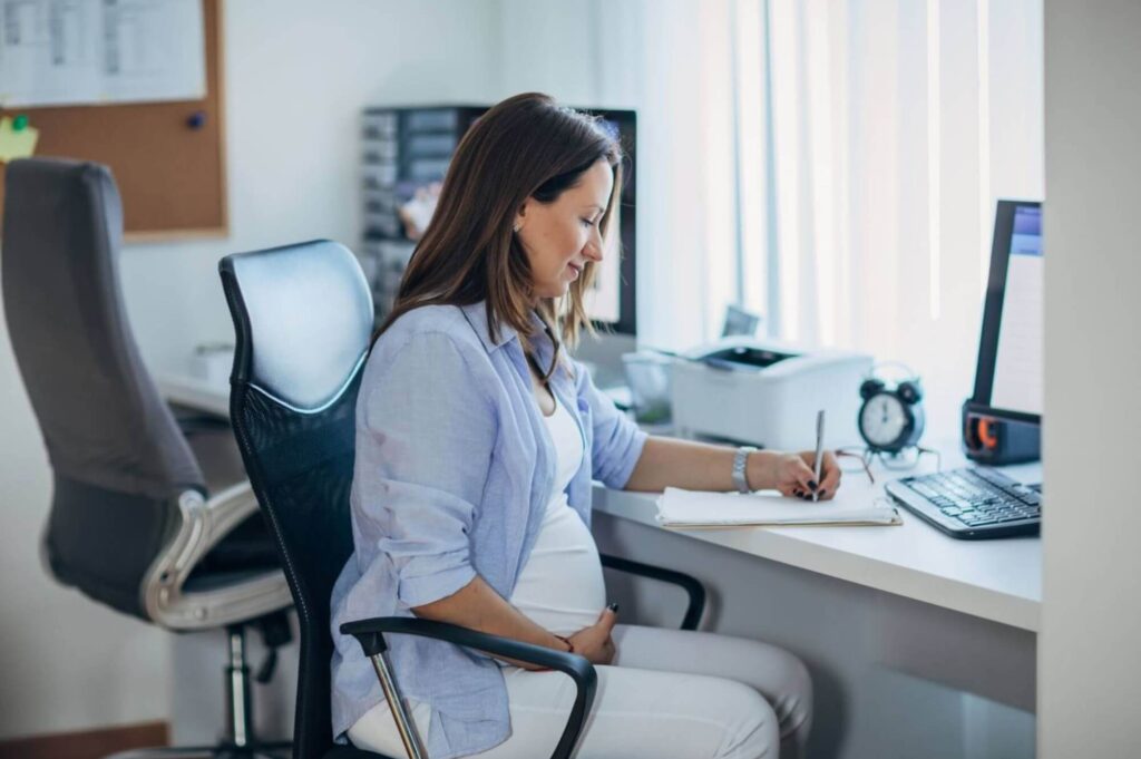 Femme enceinte travaillant à son bureau, illustrant les droits au travail pendant la grossesse