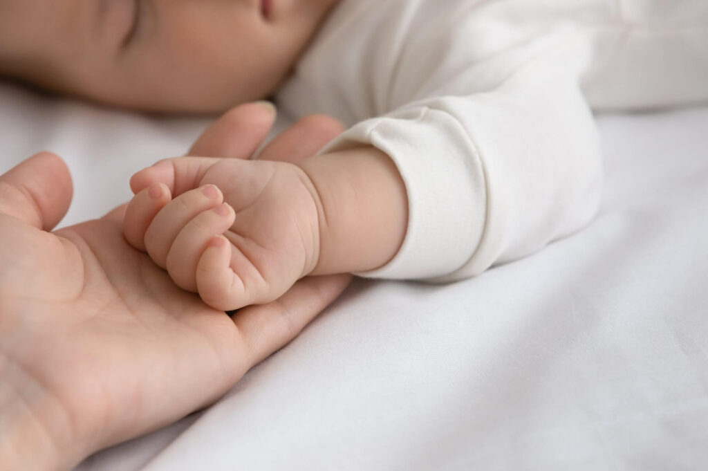 Petite main de bébé serrée dans la main d'un parent après la naissance