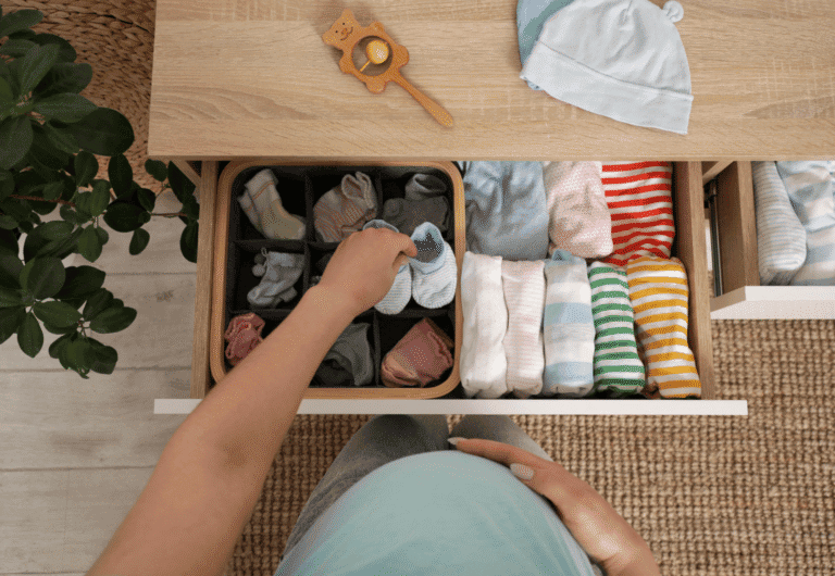femme enceinte range les vêtements de son futur bébé dans une commode