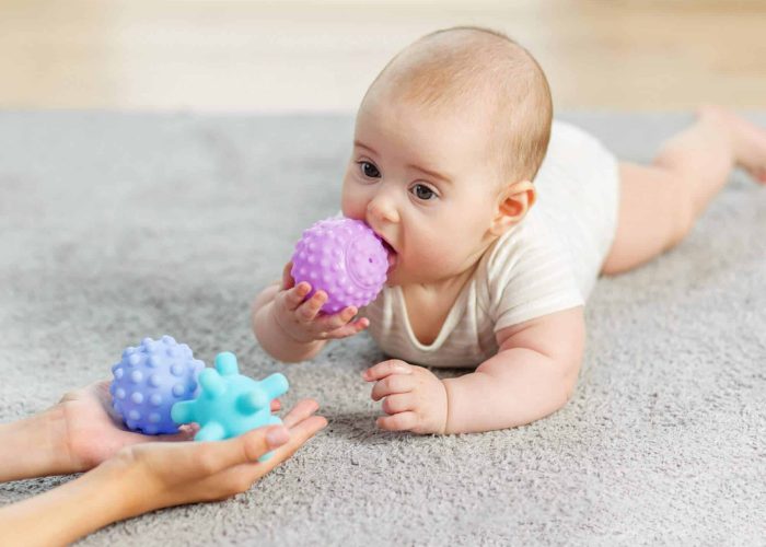 Nouveau-né sur tapis de motricité en tummy time avec jouets