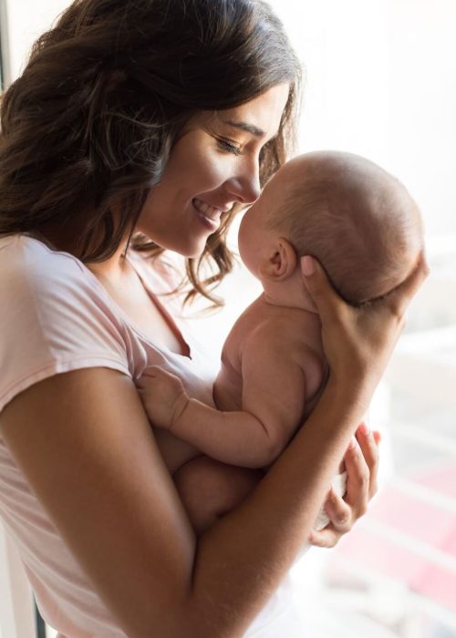 cadeau naissance jeunes parents - maman souriante tenant son nouveau-né dans les bras
